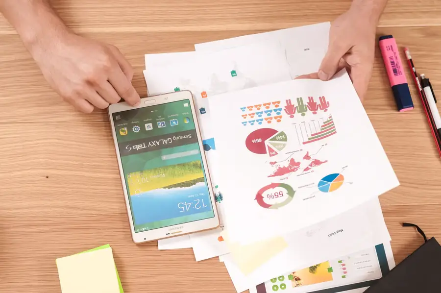 Hands reviewing printed performance charts next to a phone