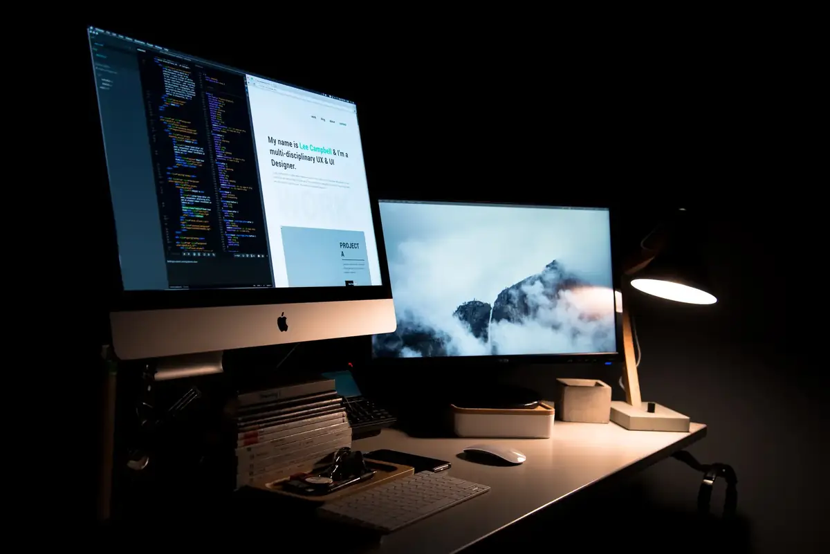 Designer's desk with two screens in a dark studio